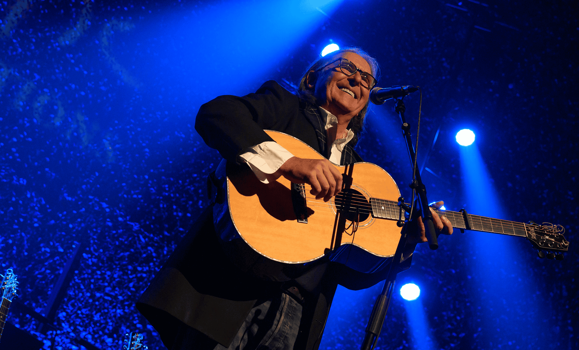 Dougie MacLean standing playing guitar