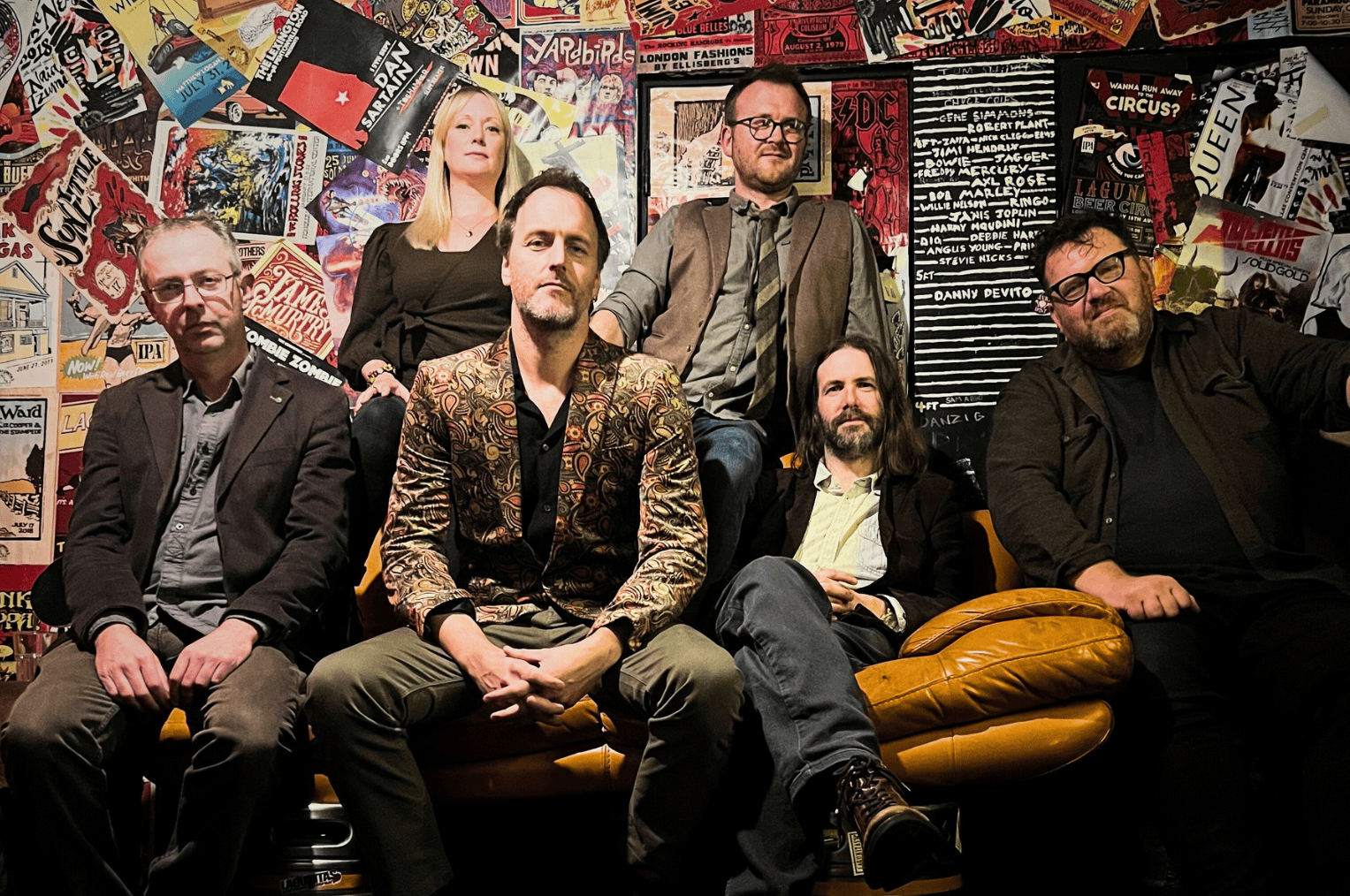 Jon Boden and band against a colourful wall gazing intently at you